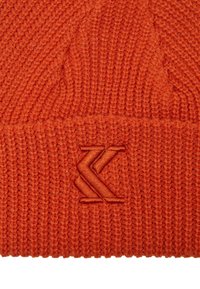Oranžist soonitud beanie, millel on ribakujundus ja mille ääres on samas värvitoonis embosseeritud logo.
