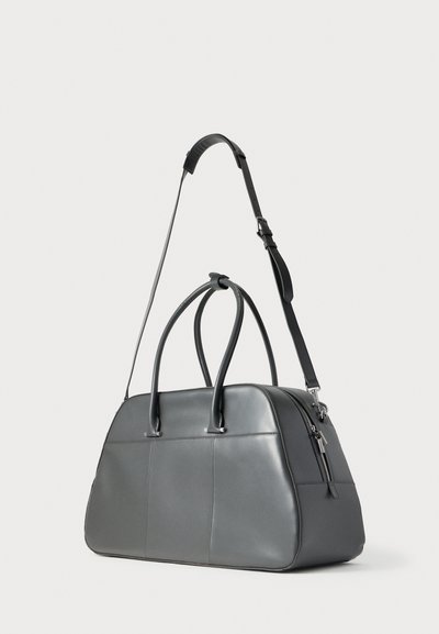 Γκρι δερμάτινη τσάντα duffel με διπλές λαβές, ρυθμιζόμενο ιμάντα ώμου και τσεπάκι με φερμουάρ. Ομαλή υφή και δομημένο σχήμα.
