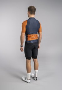 Short-sleeve cycling jersey in navy and orange, with black cycling shorts. Features a fitted design, breathable fabric, and reflective accents.