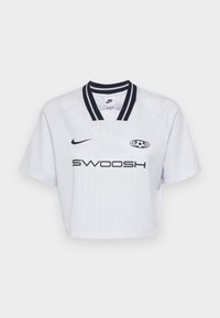 White cropped jersey with black accents, featuring a striped pattern, classic collar, and "SWOOSH" logo in bold lettering.