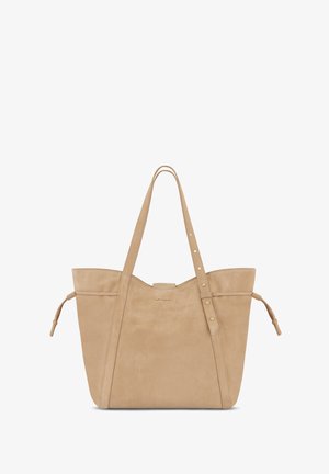 Beige suede tote bag with two elongated handles, a flat base, decorative stitching, and side ties. Gold logo accents on the front.
