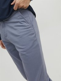 Helles graue Hosen mit schmaler Passform, glatter Textur und seitlichen Taschen, kombiniert mit einem navyblauen Langarmshirt.