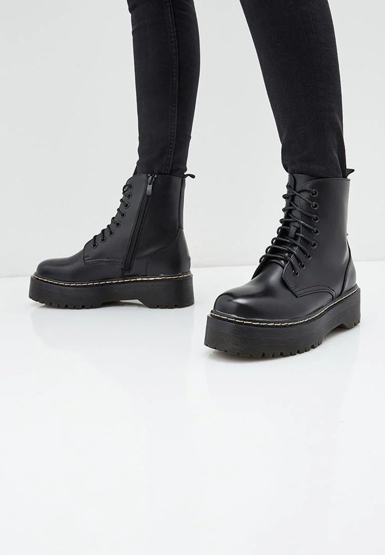Bottines noires avec une semelle plateforme épaisse, tige en cuir lisse, lacets à l'avant, fermeture éclair sur le côté et semelle en caoutchouc texturée pour une meilleure adhérence.