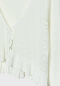 Weißer gerippter Strick-Cardigan mit vorderem Bindebandverschluss und Rüschensaumdetail, auf einem einfarbigen Hintergrund präsentiert.