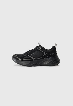 Black athletic shoes with a mesh upper, structured design, and textured sole. Features reflective accents and a pull tab at the heel.