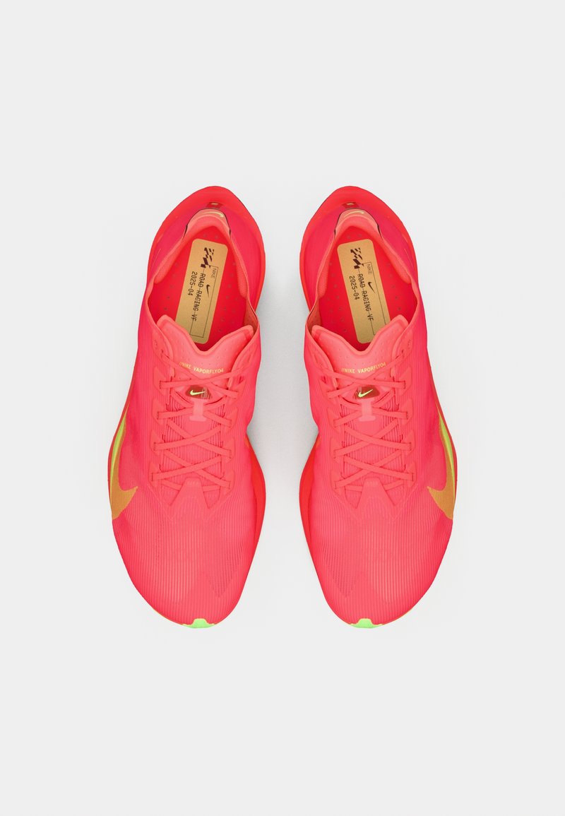 Zapatillas deportivas de color rosa brillante con un upper texturizado, silueta estructurada y suela verde. Presentan acentos en naranja y sistema de cordones tradicional.