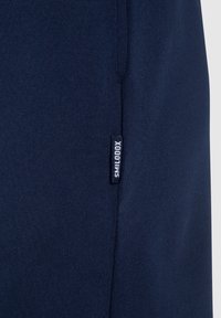Pantalones cortos deportivos de color azul marino hechos de un material suave y elástico, con una pequeña etiqueta de marca cosida en el lateral.