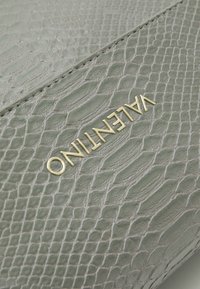 Clutch in pelle verde texture con motivo a pelle di serpente, caratterizzato dal logo "Valentino" in oro impresso sulla parte anteriore.
