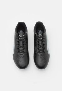 Scarpe da ginnastica nere con tomaia sintetica testurizzata, chiusura con lacci e accenti argentati lungo i lati. Presentano motivi triangolari nella zona delle dita.