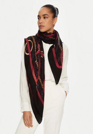 Foulard en soie avec un fond noir et des motifs de chaînes rouges et dorées, drapé élégamment autour du cou, avec une texture lisse et brillante.