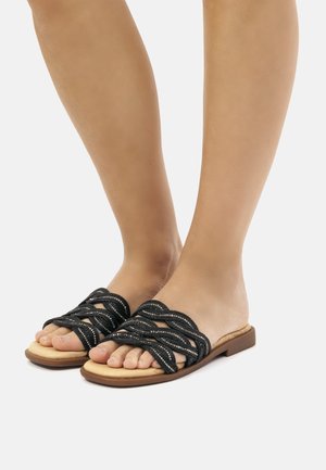 Sandali neri piatti con cinghie in tessuto intrecciato, dotati di una suola color nocciola. Design aperto, che mette in mostra le dita e l'arco del piede, adatti per un uso casual.
