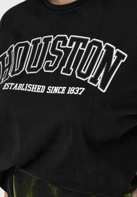 Juodas medvilninis marškinėliai su ryškiai baltu užrašu "HOUSTON" ir tekstu "ĮSTEIGTA Nuo 1837", laisva forma ir trumpomis rankovėmis.