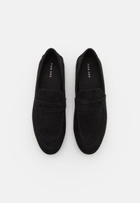 Black suede loafers with a rounded toe, a stitched seam detail, and a smooth finish. Features a decorative front strap and soft lining.