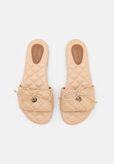 Σανδάλια σε παιδικό χρώμα με επένδυση γάζα και μαλακή δερμάτινη υφή, διακοσμητικές κορδέλες και ένα μικρό μεταλλικό λογότυπο στη λωρίδα.