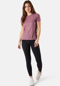 Fitted short-sleeve t-shirt in soft mauve fabric paired with black leggings. Leggings feature a side pocket and textured detailing.