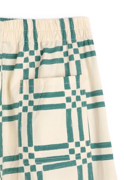 Tissu beige avec motif à carreaux vert foncé, avec une ceinture élastique et une grande poche carrée cousue sur le côté.