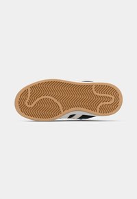 Rubber sole with a herringbone pattern in light brown, featuring a rounded shape and a contrasting black and white upper design.