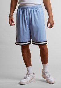 Shorts de basketball bleu clair en tissu respirant, avec des ourlets striés noirs et blancs et un logo brodé sur la jambe gauche.