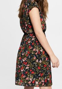 Blommig klänning med svart bakgrund, korta ärmar och figurnära midja. Dekorerad med röda, rosa och blå blommor. Lättviktigt tyg.