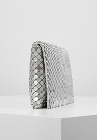 Silberne Clutch-Tasche mit hexagonalem Muster, aus metallischem Material hergestellt, mit einer eleganten, rechteckigen Form und glatter Textur.
