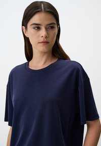 Maglietta blu navy, comoda e morbida. Presenta una scollatura rotonda e maniche corte con una texture liscia e dettagli minimi.