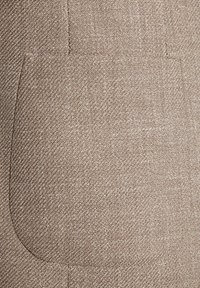 Brązowa teksturowana tkanina z subtelnym wzorem w rybi ogon. Posiada prostokątną kieszeń naszywaną, płynnie wkomponowaną w design.