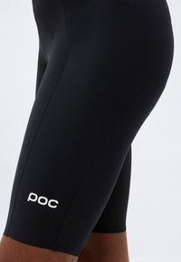Κοντινή λήψη μαύρων ποδηλατικών σορτς POC σε μπούτι ατόμου, που δείχνει το κομψό ύφασμα και το ορατό ράψιμο.