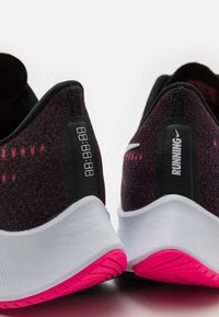 Lila gestrickte Laufschuhe mit schwarzen Akzenten, weißen Sohlen und pinken Gummisohlen; verfügen über eine Zahlenanzeige an der Ferse.