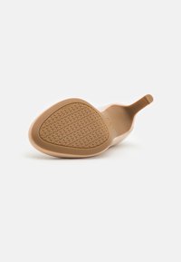 Chaussure à talon haut beige vue de la semelle, dotée d'une semelle en caoutchouc texturée avec motif et d'une pointe effilée.