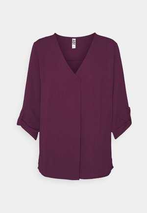 Blusa viola scuro con scollo a V e maniche a tre quarti arrotolate e abbottonate, design semplice, senza motivi o decorazioni visibili.