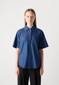 Mørkeblå denimskjorte med korte ermer, spiss krage og knapplist. Stoffet har en lett glans og subtil tekstur.