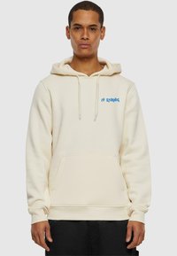 Cream-colored hoodie with a front pocket, drawstring hood, and blue "2Y Studios" embroidery on the chest. Soft, textured fabric.