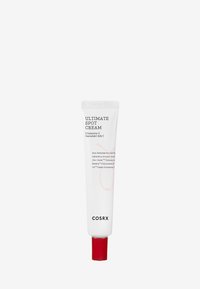 Crème ciblée Cosrx Ultimate dans un tube blanc avec un capuchon rouge. Comprend un texte clair avec les ingrédients. Le tube est cylindrique et compressible.