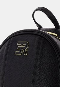 Zaino in pelle nera con superficie texturizzata, forma curva, dettagli in hardware dorato e un logo prominente. Presenta una maniglia superiore e dettagli con zip.