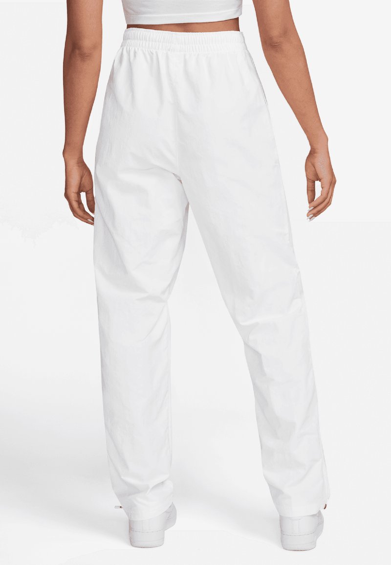 Pantaloni bianchi, leggeri e con elastico in vita, dal design dritto. Caratterizzati da una texture liscia e uno stile minimalista, abbinati a scarpe bianche.