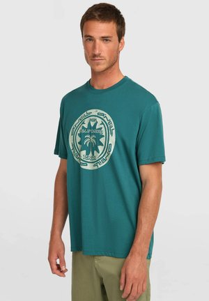 Tyrkysové tričko s krátkym rukávom a okrúhlym výstrihom; má veľký svetlozelený grafický potlač uprostred na hrudi, ktorý obsahuje text a dizajn palmy.