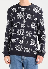 Pull en maille bleu marine avec motifs flocons de neige blancs, poignets et ourlet côtelés. Coupe confortable avec un col rond classique.