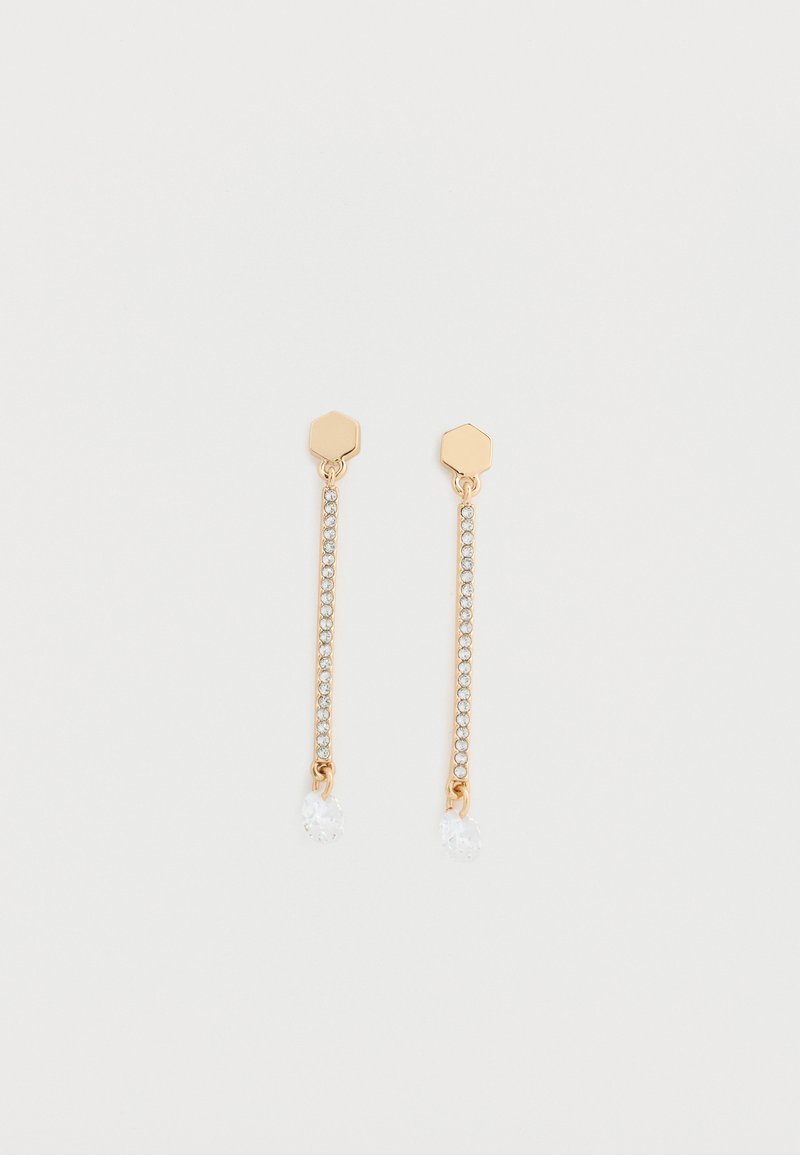 Τα σκουλαρίκια με χρυσή απόχρωση έχουν εξαγωνικό καρφί, μια σειρά από διαφανή στρας και μια στρογγυλεμένη κρεμαστή κρυστάλλινη σταγόνα στο τέλος κάθε σκουλαρικιού.