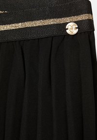 Zwarte geplooide rok met een textuur waistband met een gouden metalen strook en een decoratieve ronde knoop. Zachte, vloeiende stof.