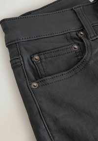 Jeans in denim nero con una texture liscia, cuciture a contrasto, una tasca frontale con rivetti metallici e una vita aderente.