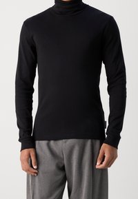 Schwarz, langärmliges Rollkragen-Shirt aus glattem Strickstoff. Hat ein tailliertes Design mit flachen Nähten und einem Etikett an der Seite.