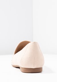 Chaussure plate en daim beige avec un bout pointu, des coutures minimales, une texture lisse et un petit talon rond. Pas de matériel ou embellissements visibles.