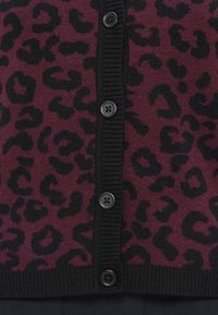 Maroon cardigan with black leopard print, featuring a ribbed knit texture, black buttons, and a classic button-up front design.