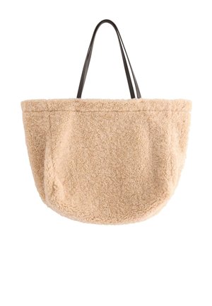 Beige, fuzzy tote bag med en blød, struktureret overflade; har lange sorte stropper; rund form med sidelommer til opbevaring.