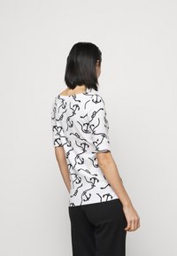 Biały T-shirt z krótkim rękawem, ozdobiony czarnym wzorem kotwicy i łańcucha, z okrągłym dekoltem i prostym tyłem.