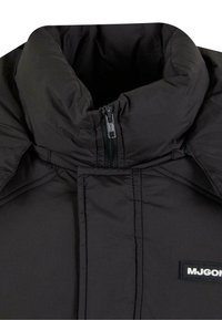 Schwarze Puffjacke mit hohem Kragen, Frontreißverschluss und gesteppter Optik. Mit einem Logopatch auf der linken Seite. Strukturiertes Gewebe.