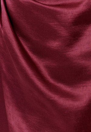 Tela de terciopelo burdeos profundo, suave y plegada, con suaves reflejos de luz que destacan su textura y brillo.