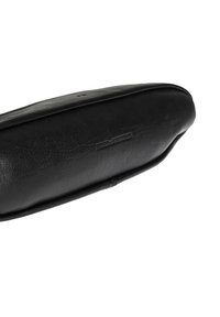 Czarne skórzane płaskie buty z zaokrąglonym noskiem i niskim obcasem, z wytłoczonym logo marki na górnej stronie.