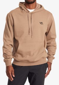 Sweat à capuche beige avec une poche frontale, une capuche ajustable à cordon et un petit logo noir en haut à gauche. Tissu doux avec des poignets côtelés.
