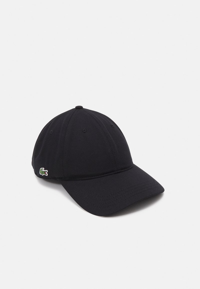 Casquette de baseball noire avec une visière courbée et un petit logo crocodile vert brodé sur le côté, sur un fond blanc uni.